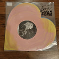 Vinyl record in packaging with Taylor Swift's face on a pink and yellow background